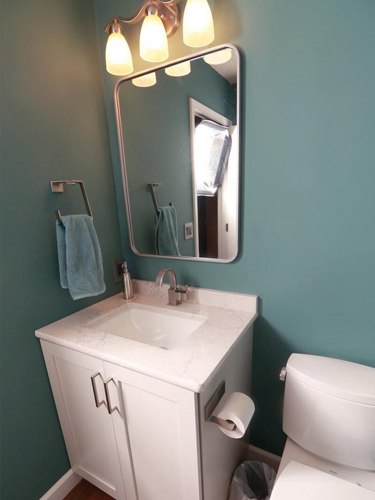 modern updated bathroom with teal walls and white vanity