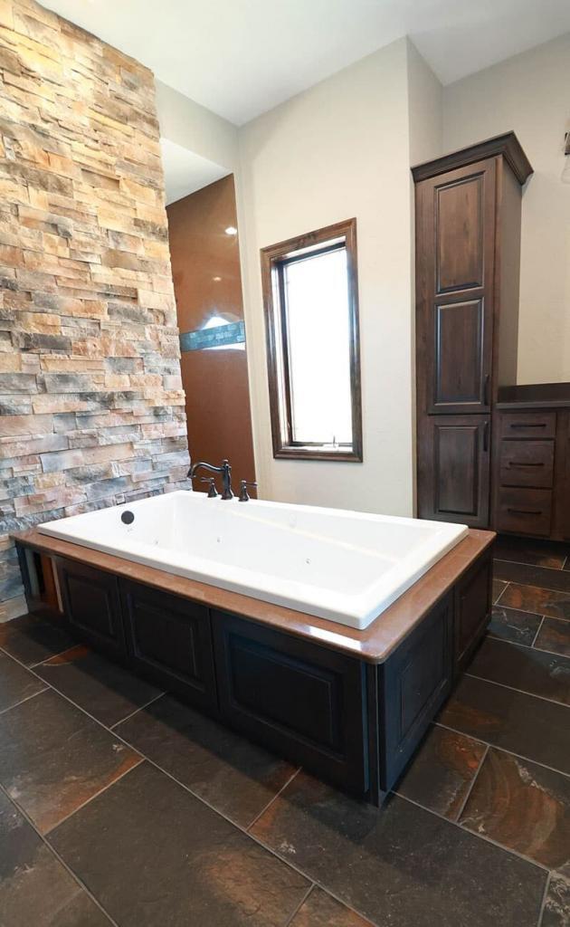 stone wall bathroom with dark cabinets