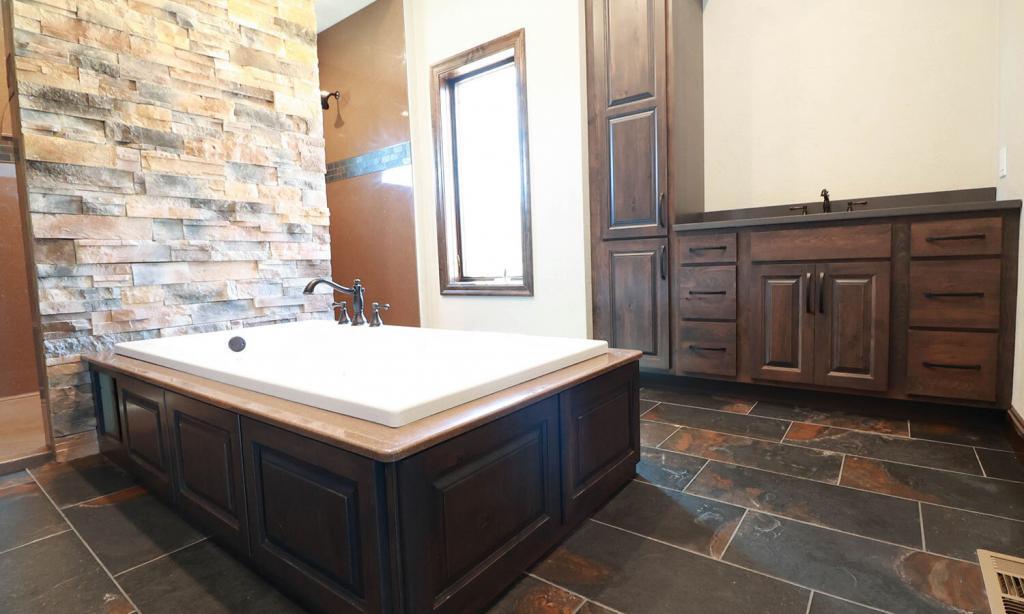 stone wall bathroom with dark cabinets