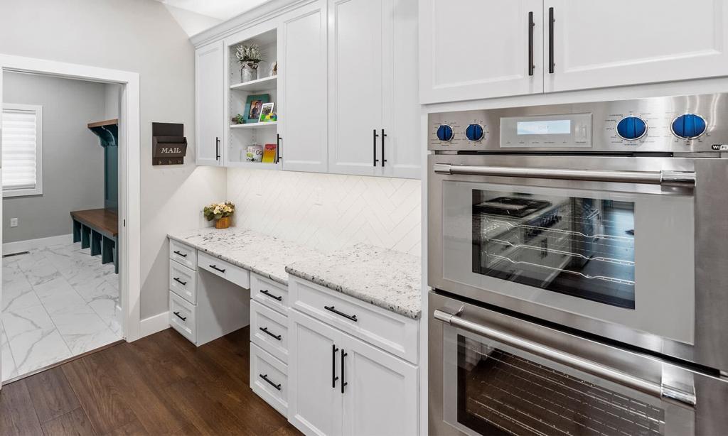 white built in desk next to dual oven in stainless steel