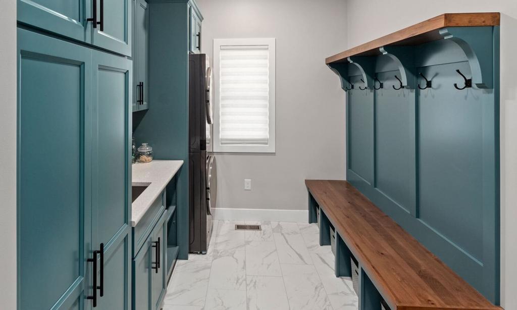 modern laundry room with green cabinets and builtin seating